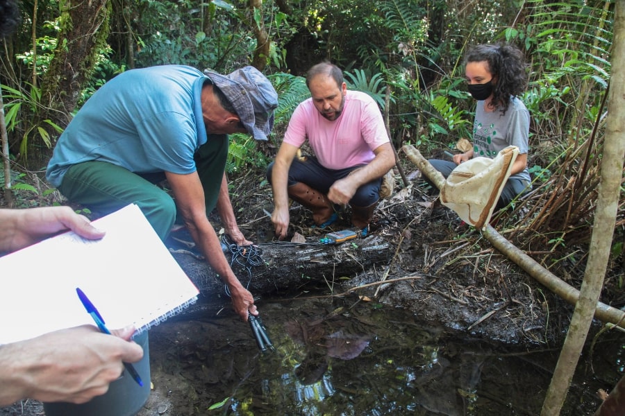 foto de pessoas coletando amostra de água de nascente na floresta
