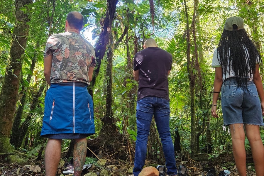 Foto de 3 pessoas de costas, na floresta, olhando para a mata
