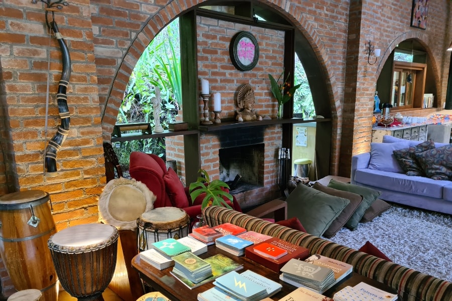 Foto de detalhe do restaurante, com livros e atabaques no canto da sala