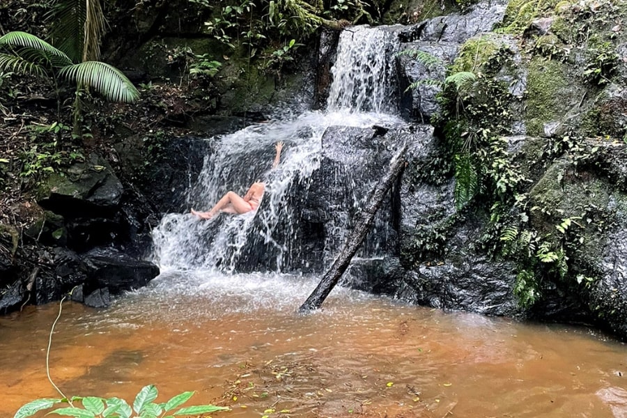 Foto de uma mulher tomando uma banho da cachoeira