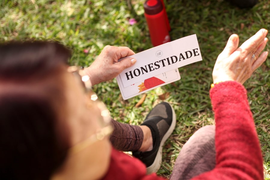 Foto de uma mulher segurando um papel com a palavra Honestidade