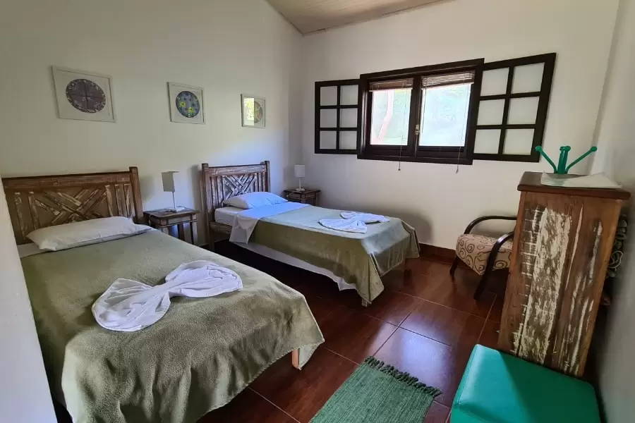 Foto de um grande quarto aconchegante, com duas camas. uma de casal e uma de solteiro, com uma janela alta
