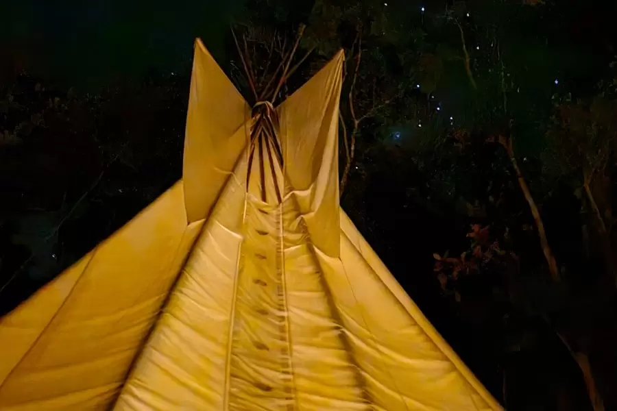 Foto da ponta de uma tenda amarela na luz do luar