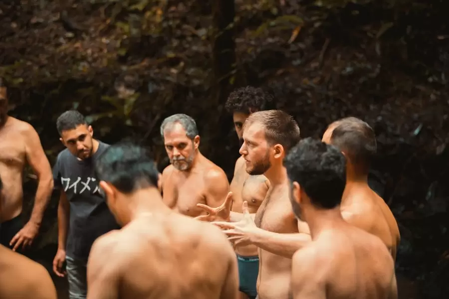 Foto de homens em pé, sem roupa, ouvindo explicações