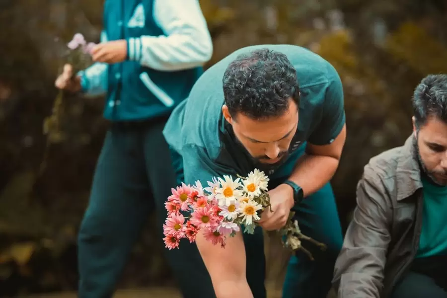 Foto de homem colhendo flores brancas e cor de rosa