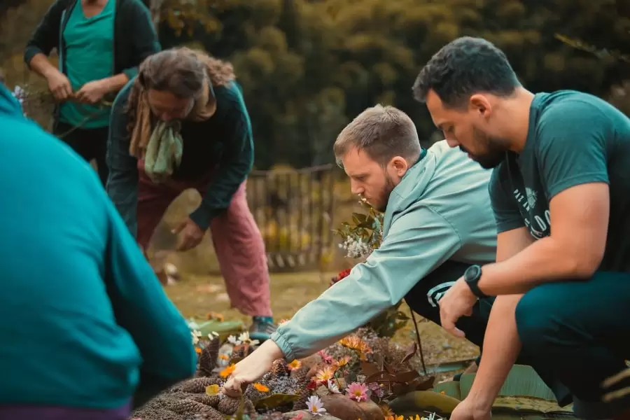 Foto de homens abaixados, mexendo na terra com as mãos