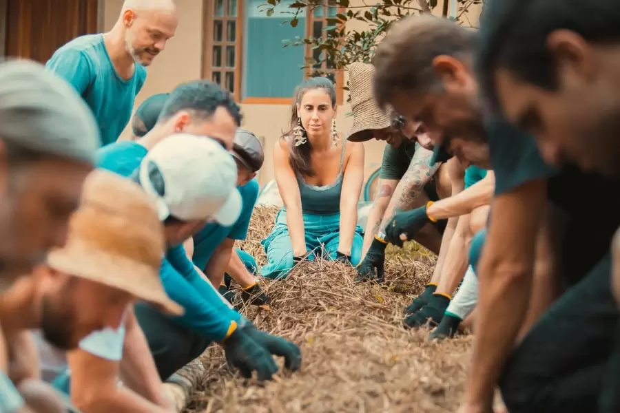 Foto de pessoas agachadas, mexendo na terra com as mãos