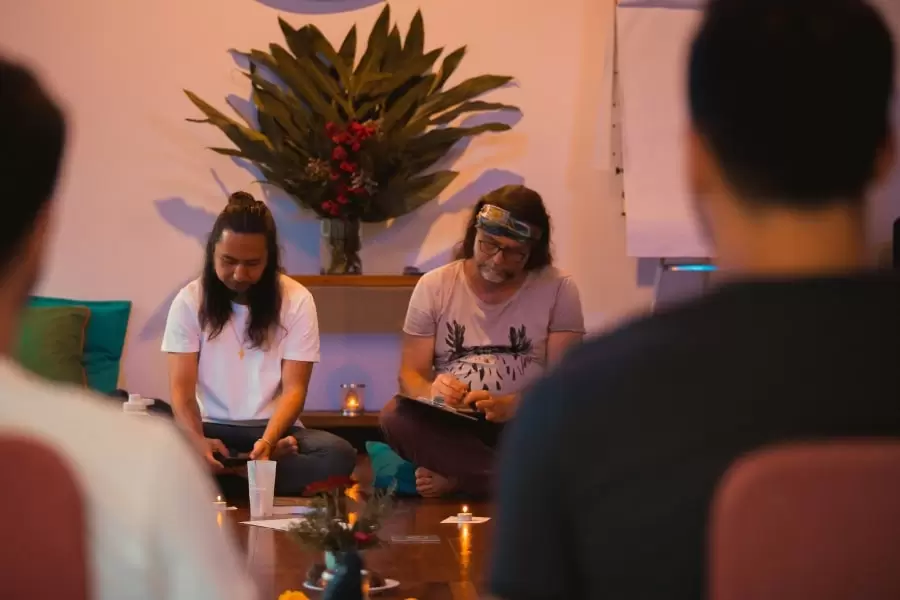 Foto de homens sentados no chão, numa sala