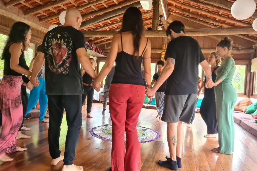 Roda de dança circular com pessoas de mãos dadas.