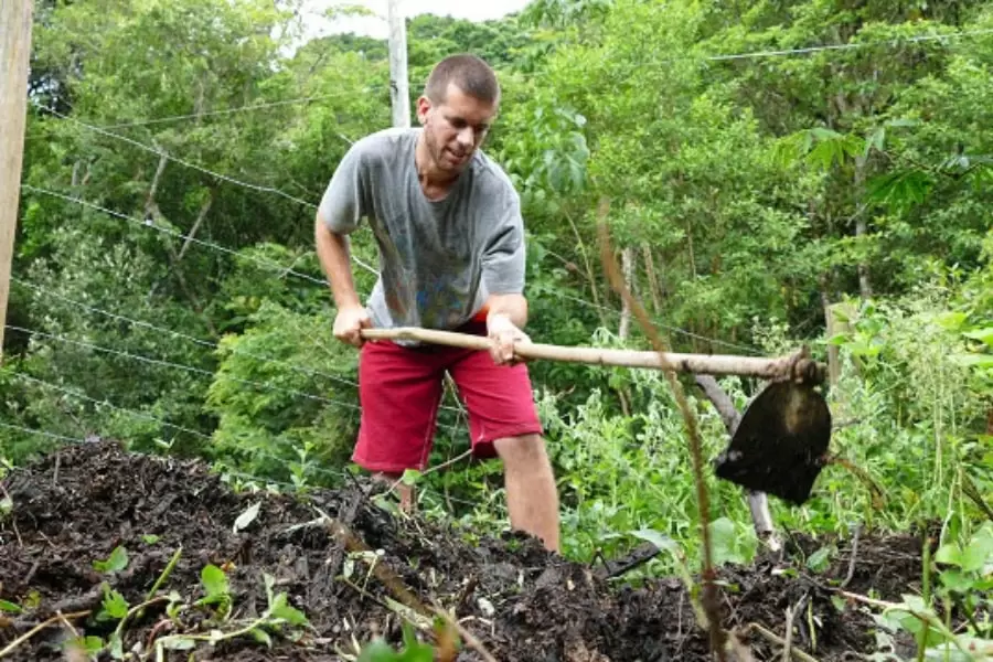 Foto de uma homem trabalhando na terra, com uma enxada